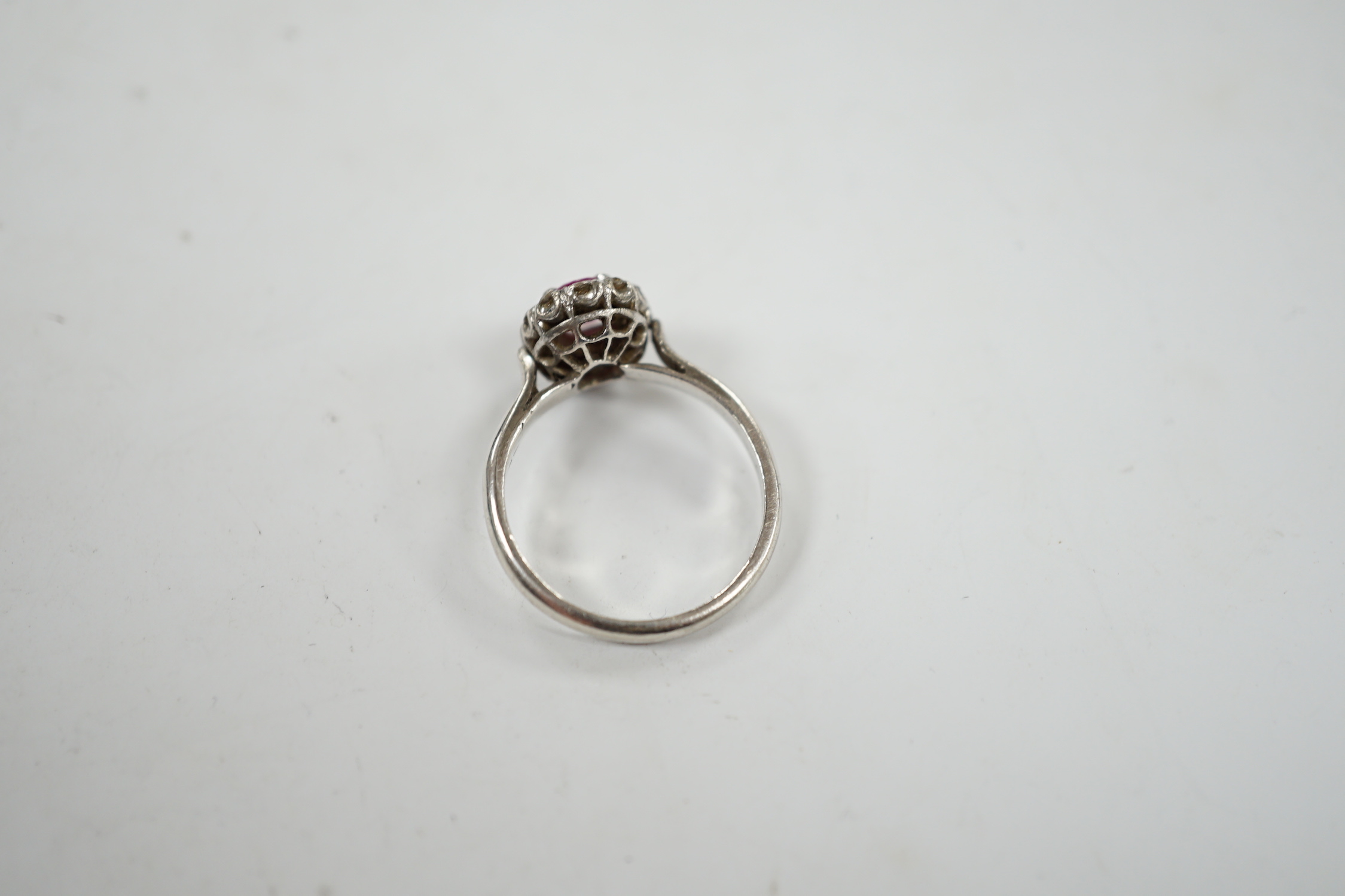 A white metal, synthetic? ruby and diamond set oval cluster ring, size P, gross weight 3.3 grams.
